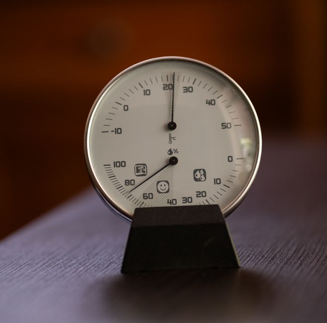 An analogue thermometer and hygrometer dial on a small stand