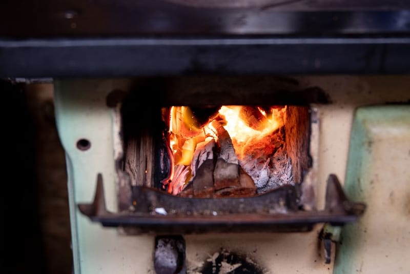 Wood-burning sauna stove with flames visible through the firebox