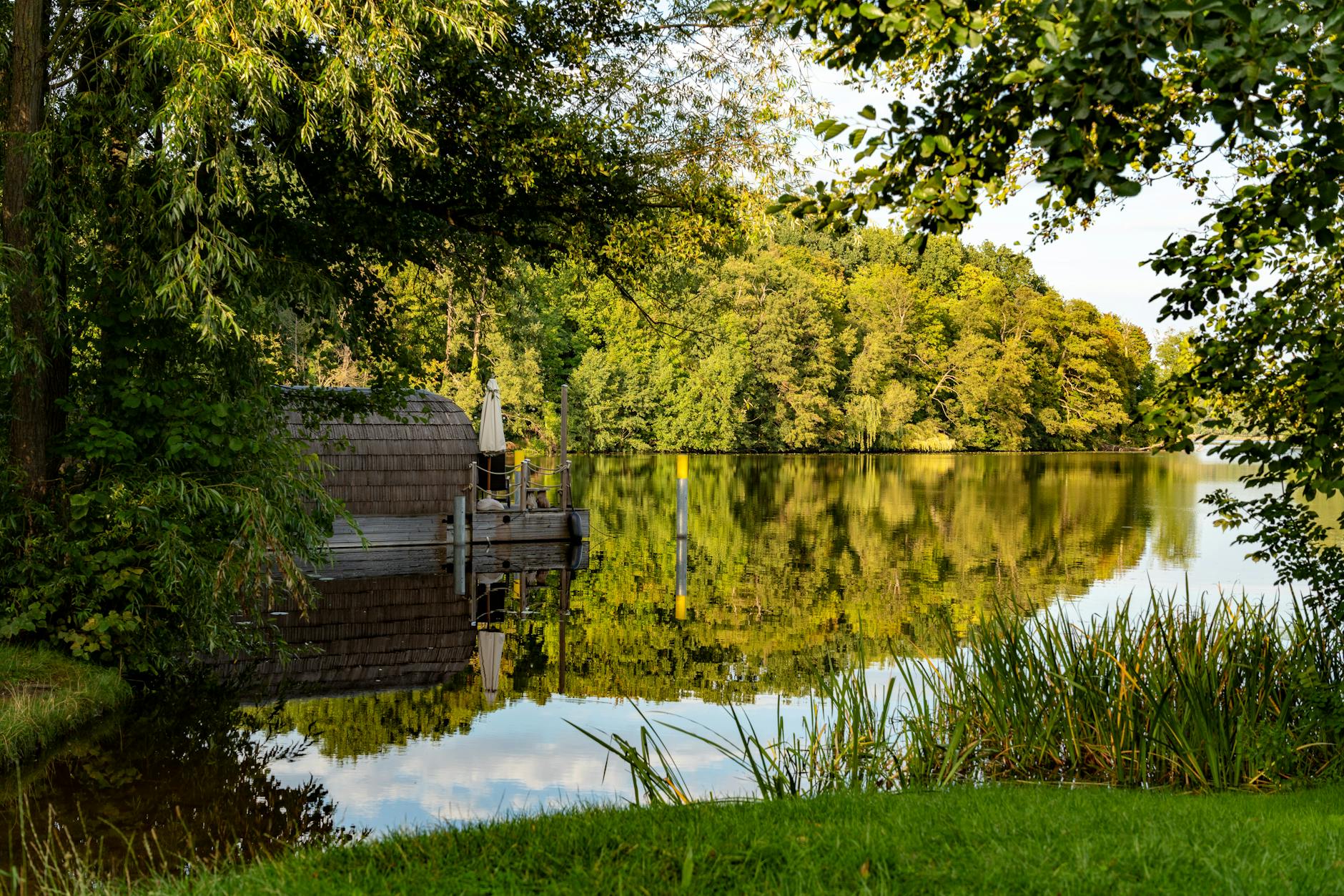 Wooden sauna cabin at the edge of a forest lake with clear water reflections